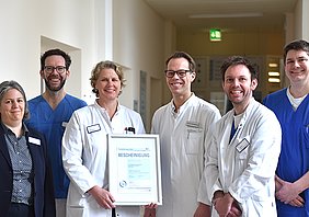 Das Team des Lokalen Traumazentrums am St. Hildegardis Krankenhaus präsentiert die Bestätigung über die Rezertifizierung